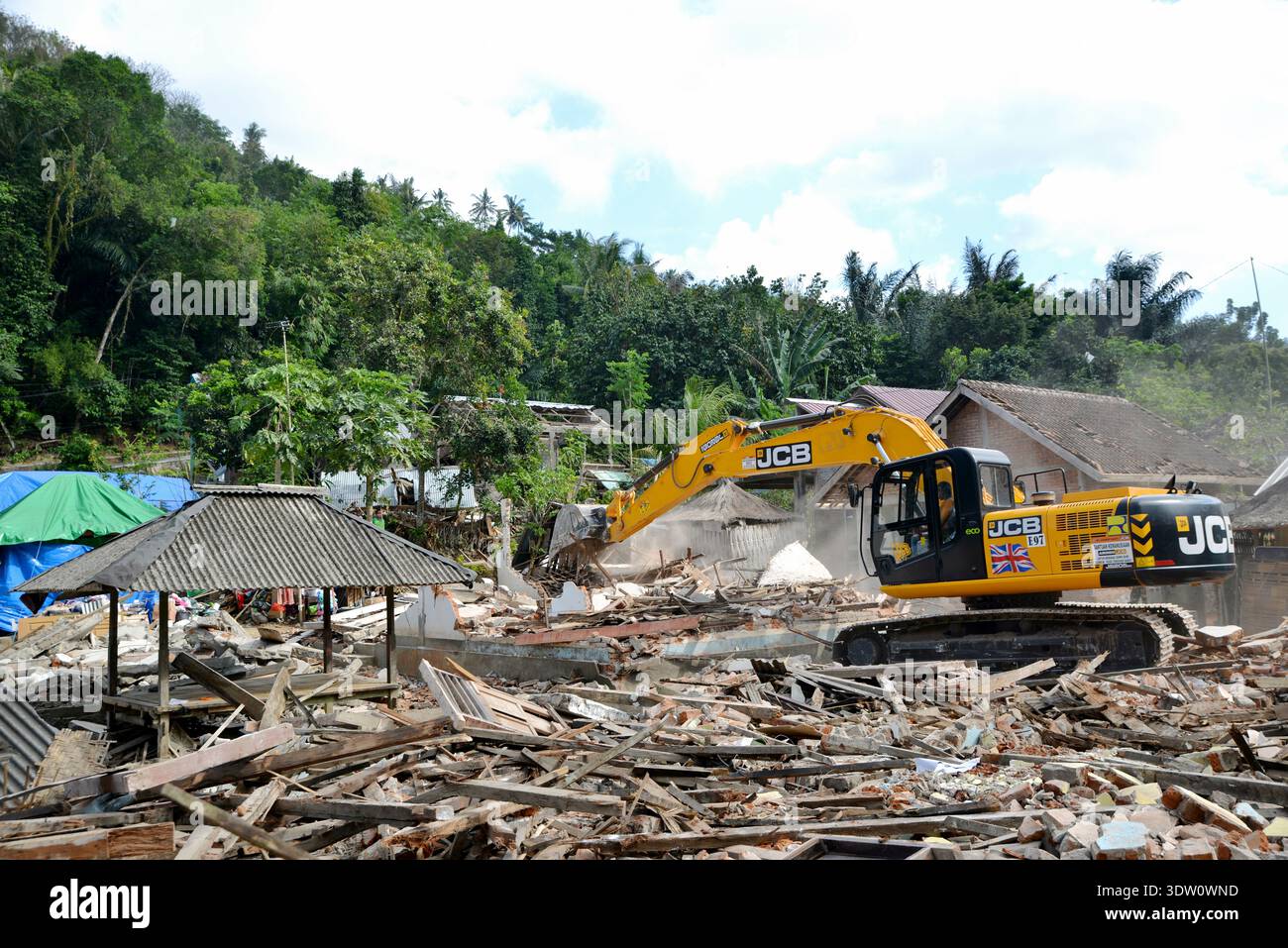 Escavatore JCB che pulisce i detriti del terremoto a Lombok, Indonesia Foto Stock