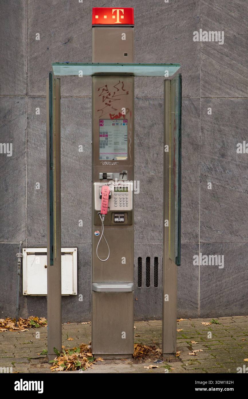 Moderno montante per telefono in argento Deutsche Telekom con ricevitore rosa e graffiti davanti a una facciata in pietra grigia a Lipsia, Germania Foto Stock