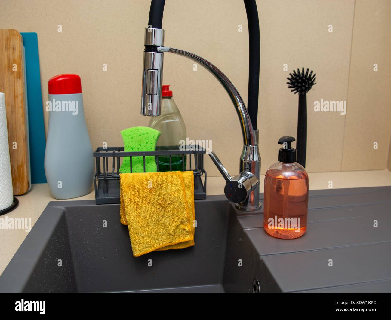 Angolo lavello da cucina con sapone liquido, spugna, panno per pulizia, detersivo per piatti e salviette di carta. Allestimento per la pulizia domestica che illustra la governante Foto Stock