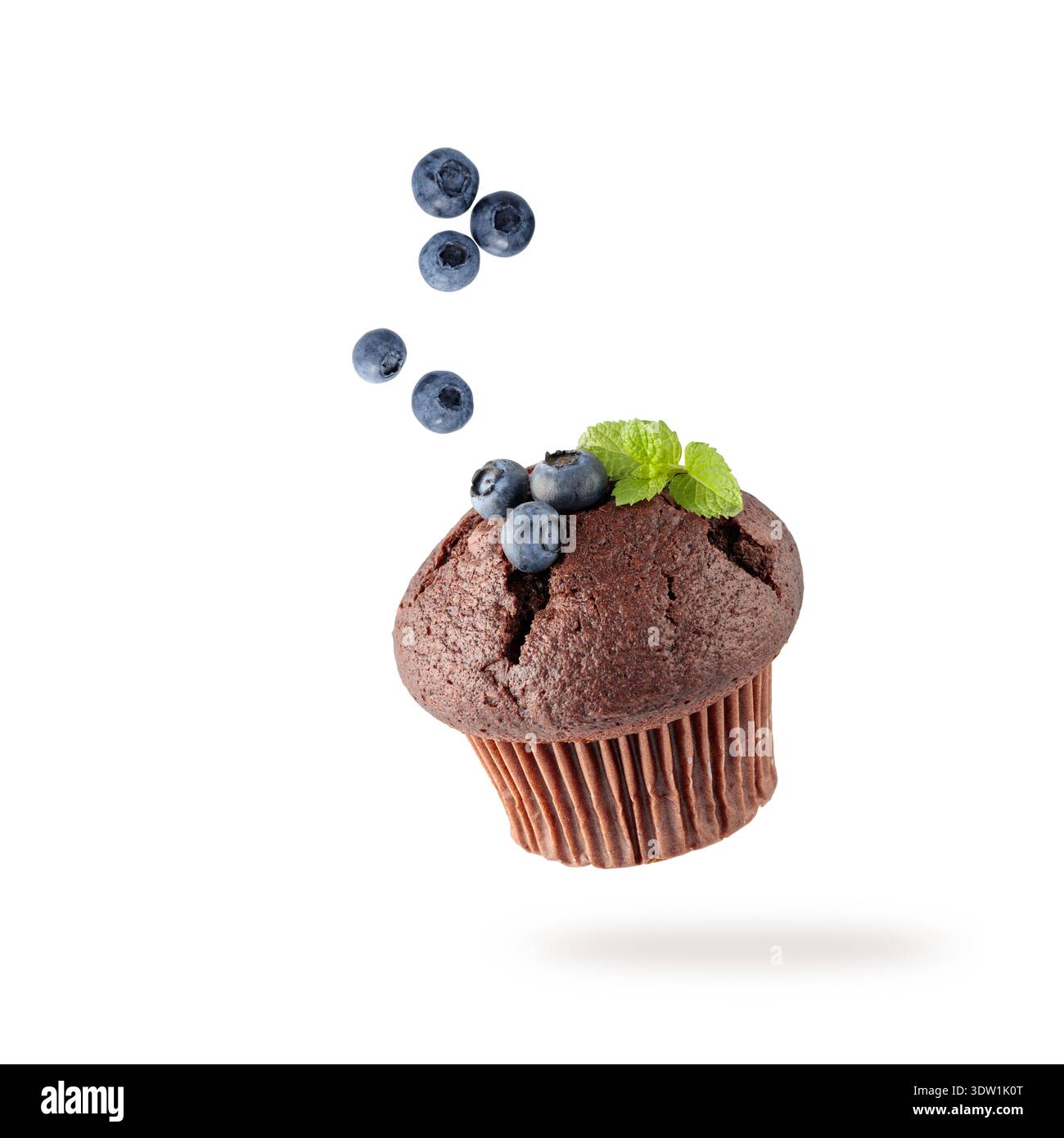 Muffin singolo al cioccolato appena sfornato con mirtilli e foglie di menta che volano su sfondo bianco. Dolce cupcake che cade. Carta di pasticceria con copia spp Foto Stock