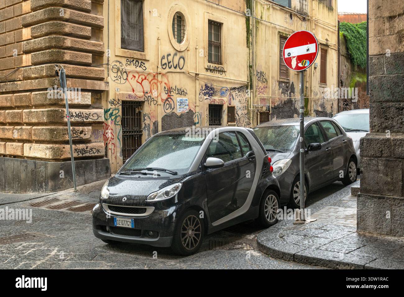 Piccole auto parcheggiate molto vicine in una strada di Catania, Sicilia, Italia. Foto Stock