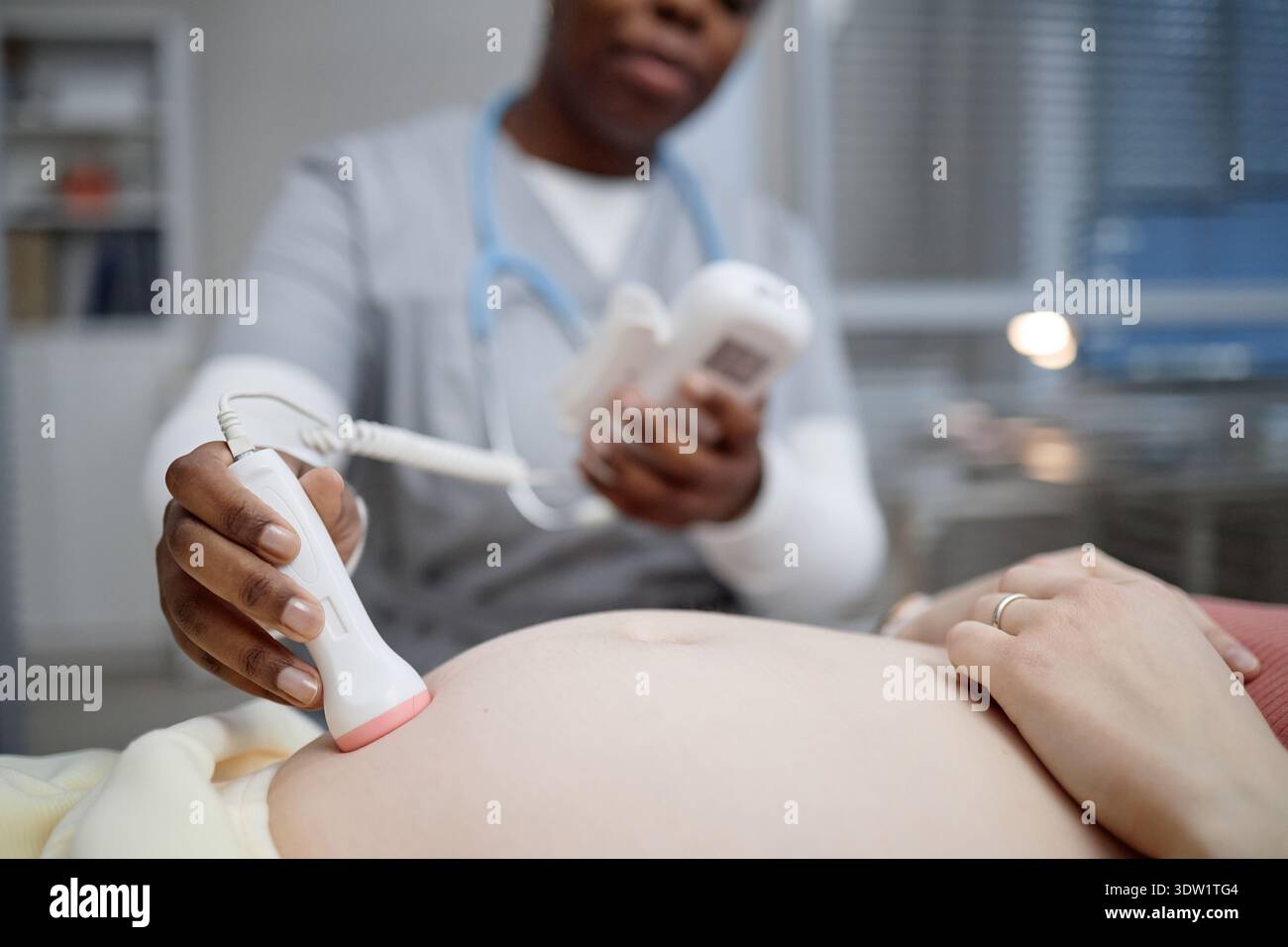 Dottoressa donna nera che esegue ultrasuoni che esamina la donna incinta addome Foto Stock