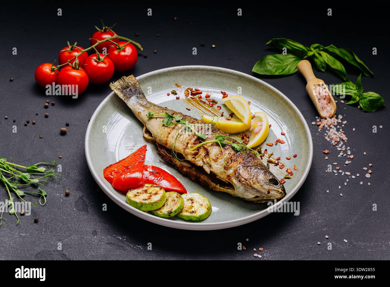 Pesce intero alla griglia con verdure e limone servito su un elegante piatto del ristorante Foto Stock