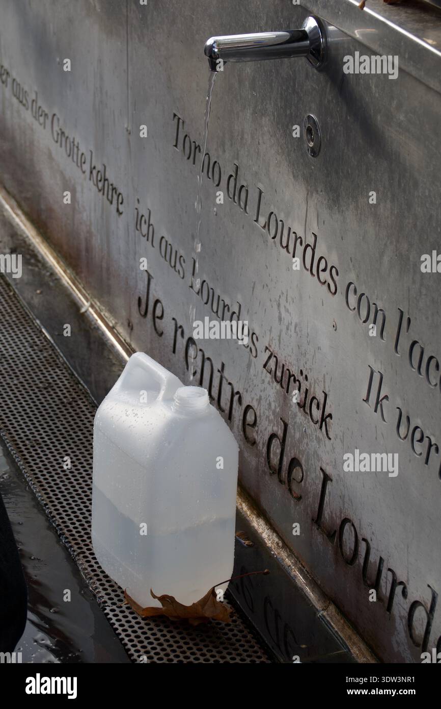 Raccolta di acqua curativa da un rubinetto a Lourdes Foto Stock
