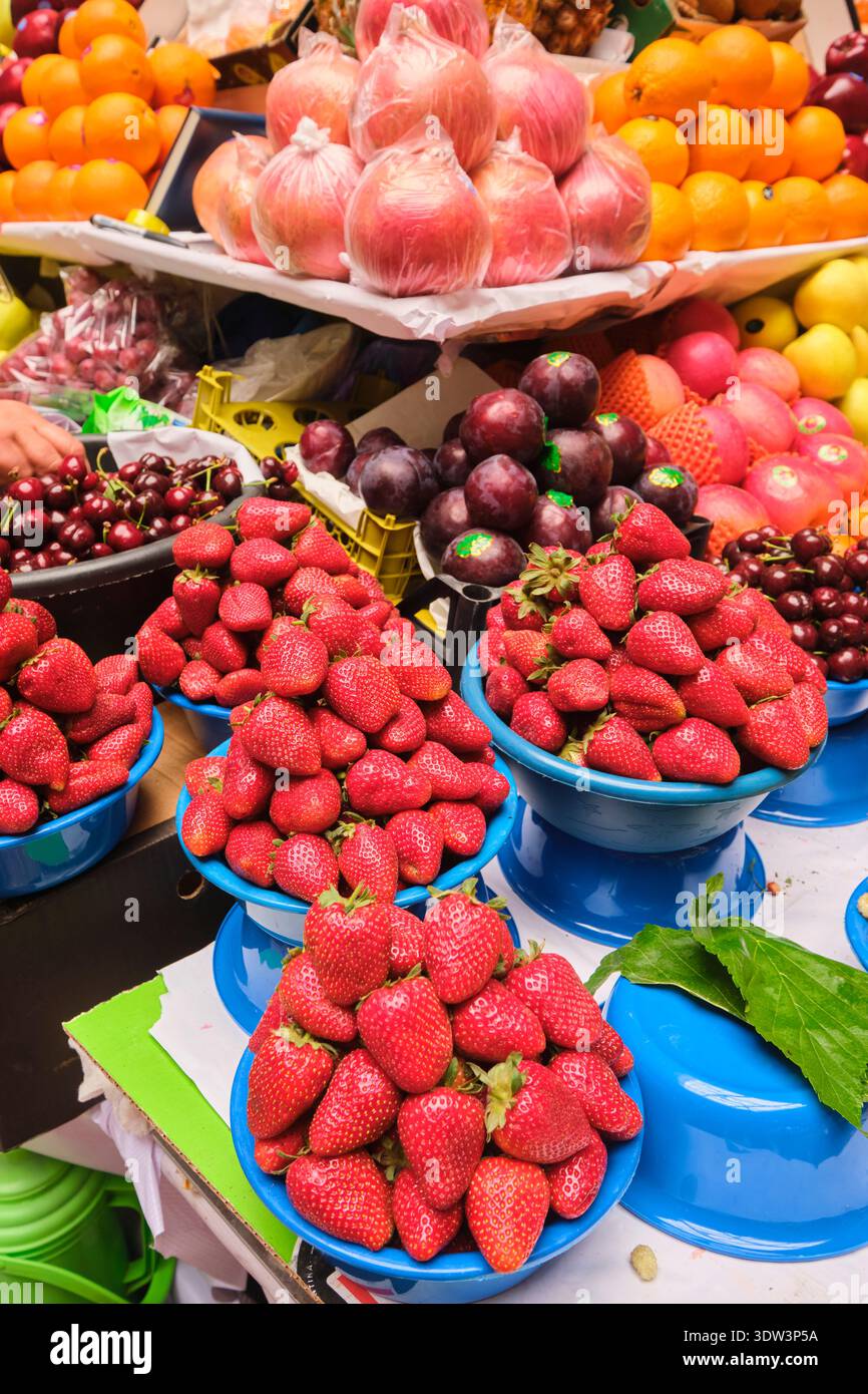Una varietà di frutta fresca, tra cui fragole, mele, prugne e arance in vendita. Al grande mercato alimentare locale di Mehrgon. A Dushanbe, Tagikistan. Foto Stock