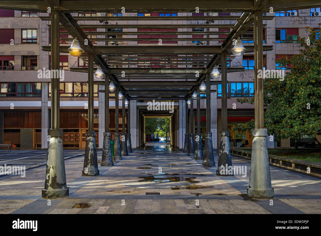 Struttura a pergola metallica con luci sospese e pilastri intemprati in una piazza pubblica che conduce ad un edificio moderno a Pamplona, Spagna Foto Stock