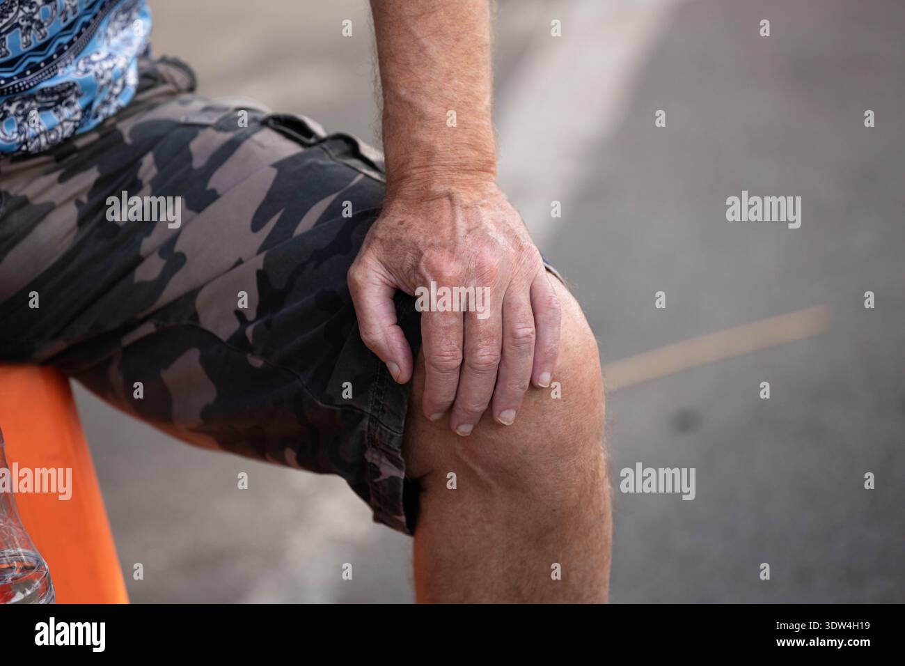 Mano dell'uomo appoggiata sul ginocchio, stile di vita cittadino, pelle di mano maschile e texture delle unghie, primo piano, al Chatuchak Market. Foto Stock