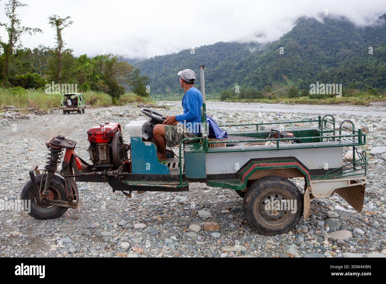 Man guida un trattore a mano kuliglig attraverso il letto roccioso del fiume a Divilican nelle Filippine mostrando un trasporto rurale improvvisato in una provincia remota Foto Stock