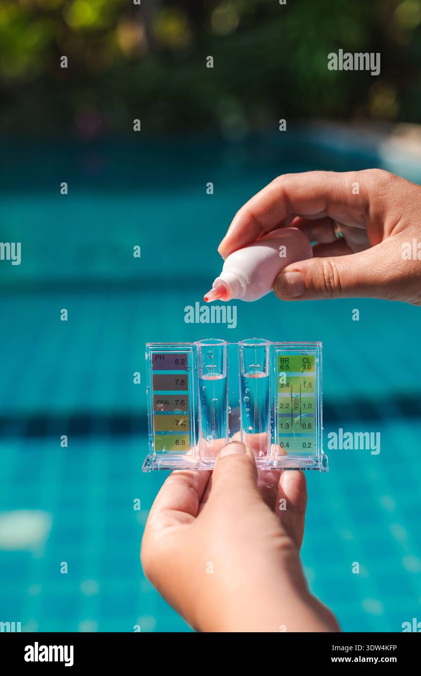 Kit di prova dell'acqua di piscina con mano per misurare i livelli di pH e cloro in una piscina blu chiaro, manutenzione ordinaria della piscina e controllo della qualità dell'acqua Foto Stock