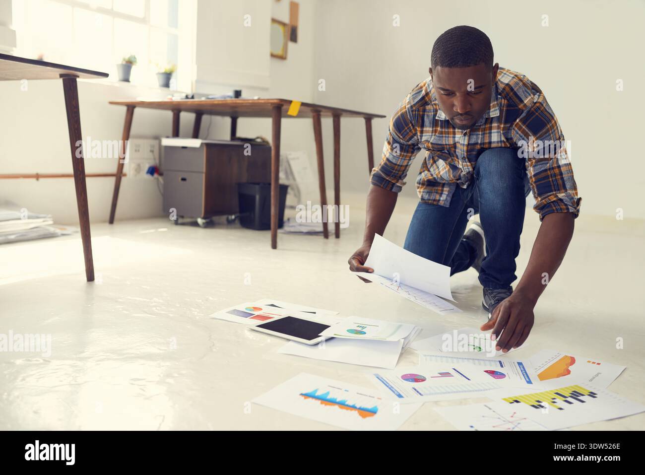 Documenti cartacei, lettura o uomo nero sul pavimento in agenzia creativa, ricerca o analisi dei dati per le tendenze dei consumatori. Vendite del marchio, startup o marketer con Foto Stock