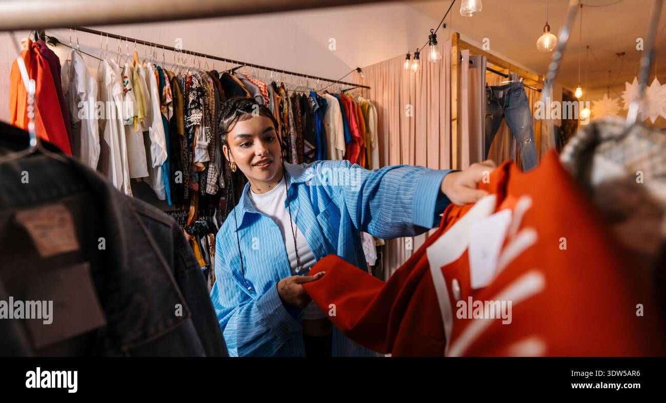 Il cliente sceglie Coat. Gli amanti dello shopping sono immersi nella navigazione e nella sensazione di diversi stili di abbigliamento Foto Stock