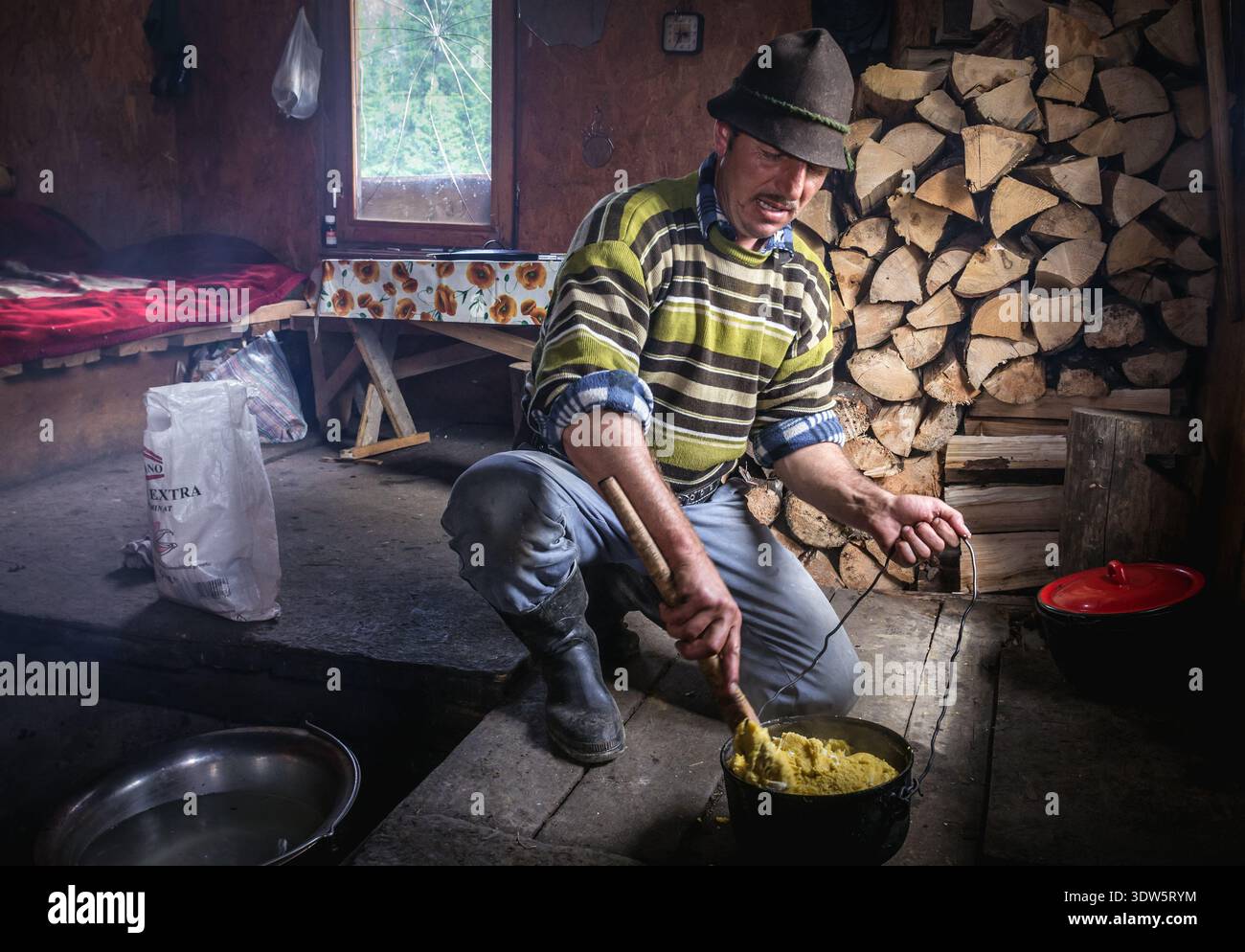 L'uomo prepara Mamaliga in una capanna di pastore di montagna in località di Borsa nelle montagne Rodna, che si trova nella Contea di Maramures della Romania del Nord Foto Stock