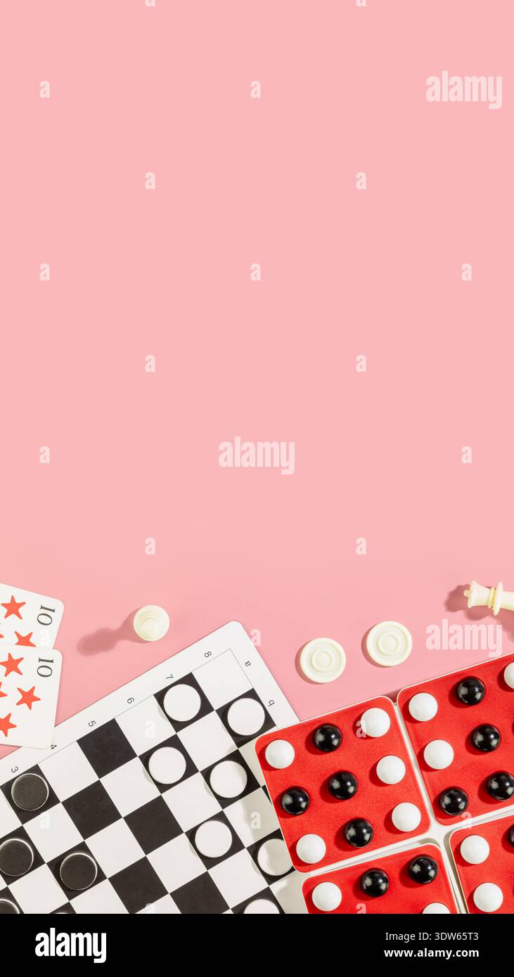 Giochi da tavolo in piano con dama, domini e carte da gioco su sfondo rosa. Concetto di divertimento notturno per tutta la famiglia, atmosfera amichevole da competizione, Home E. Foto Stock