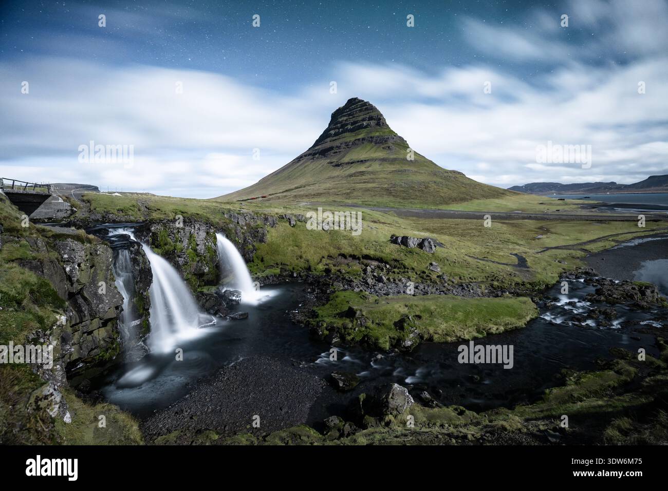 Vista delle cascate che si tuffano nel fiume sotto la maestosa montagna Kirkjufell sotto un cielo stellato, Grundarfjarðarbær, Grundarfjarðarbær, Foto Stock