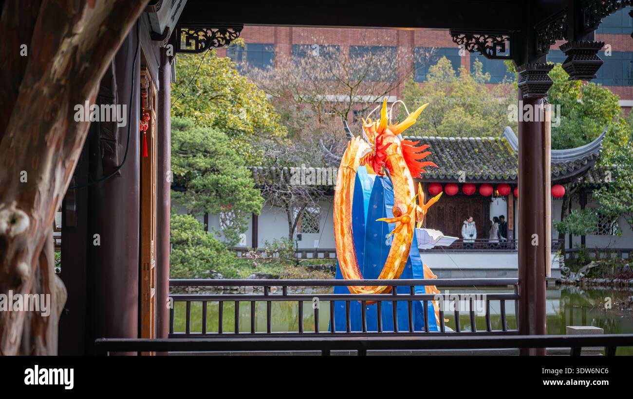 Vista di una vivace scultura di drago blu e oro che si erge orgogliosamente accanto al tranquillo laghetto, incorniciata da opere in legno ornate, LAN su Chinese Gardens, Portland, Foto Stock