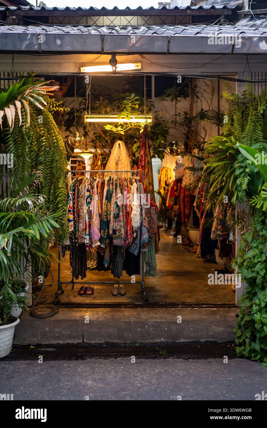 Negozio di abbigliamento vintage in Asia circondato da lussureggianti piante tropicali. shopping sostenibile, di seconda mano Foto Stock