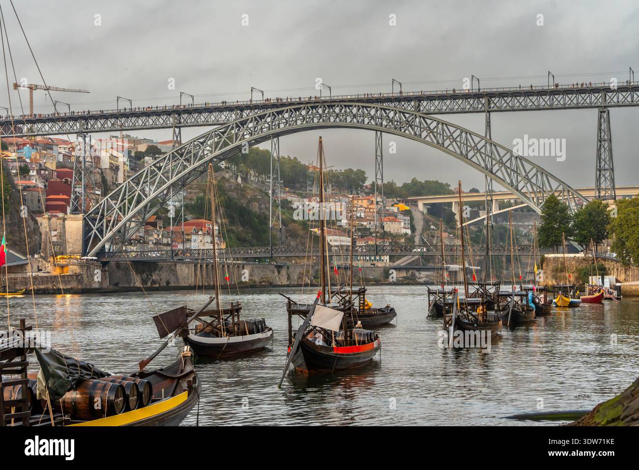 Il paesaggio storico di Porto, caratterizzato da piccole barche rabelo sul fiume Douro sotto l'iconico ponte, Portogallo Foto Stock
