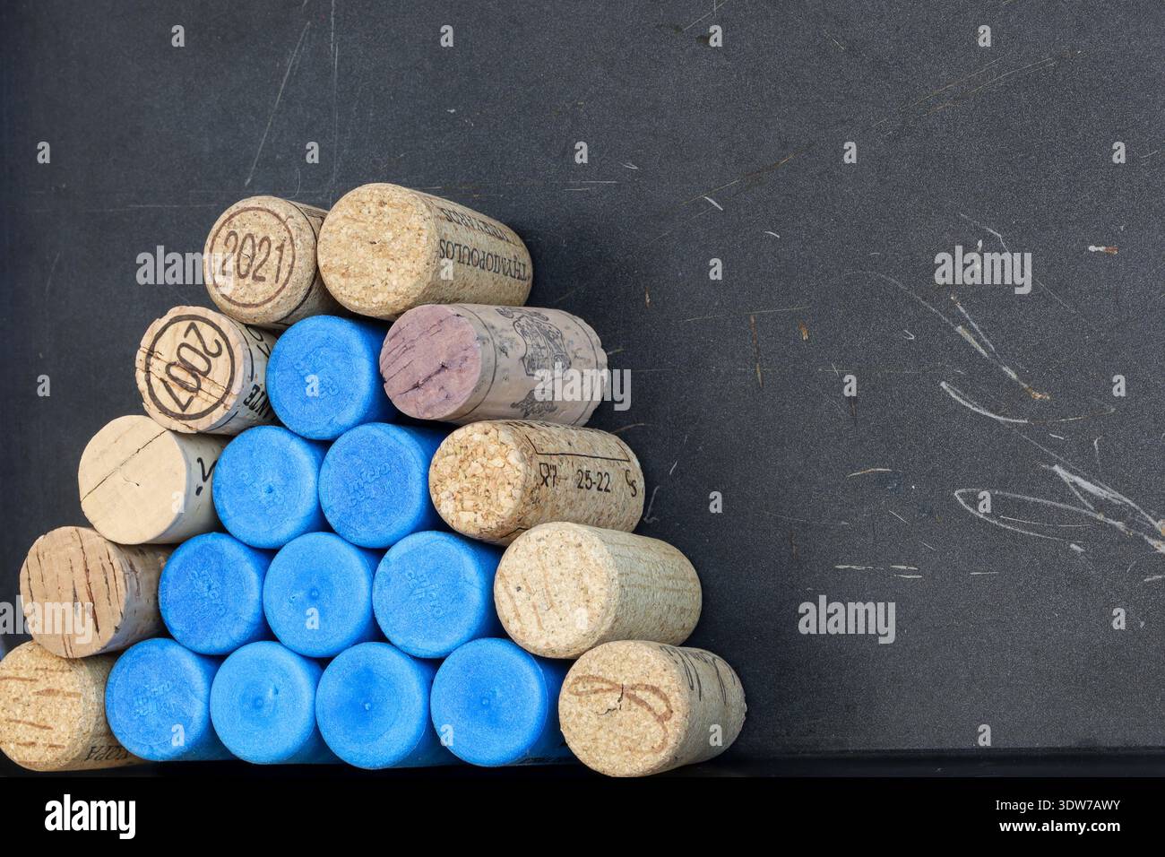 Atene, Grecia - 15 febbraio 2026: Sugheri di vino sintetico e naturale impilati disposti in una formazione piramidale su una superficie scura. Foto Stock