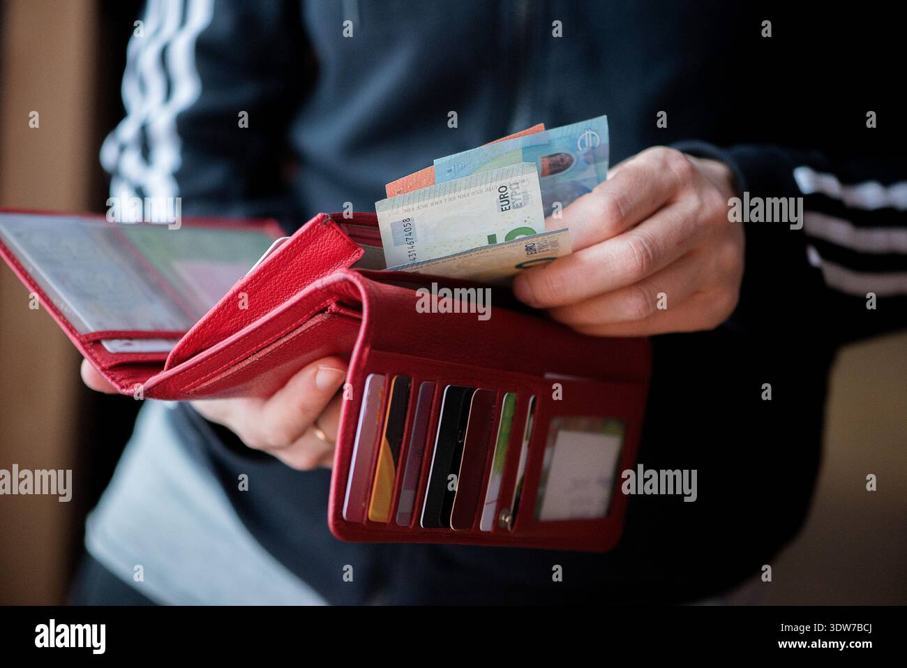 Mani che tengono un portafoglio aperto con banconote e carte, simboleggiano la finanza personale, le spese, i risparmi e le decisioni economiche quotidiane. Foto Stock