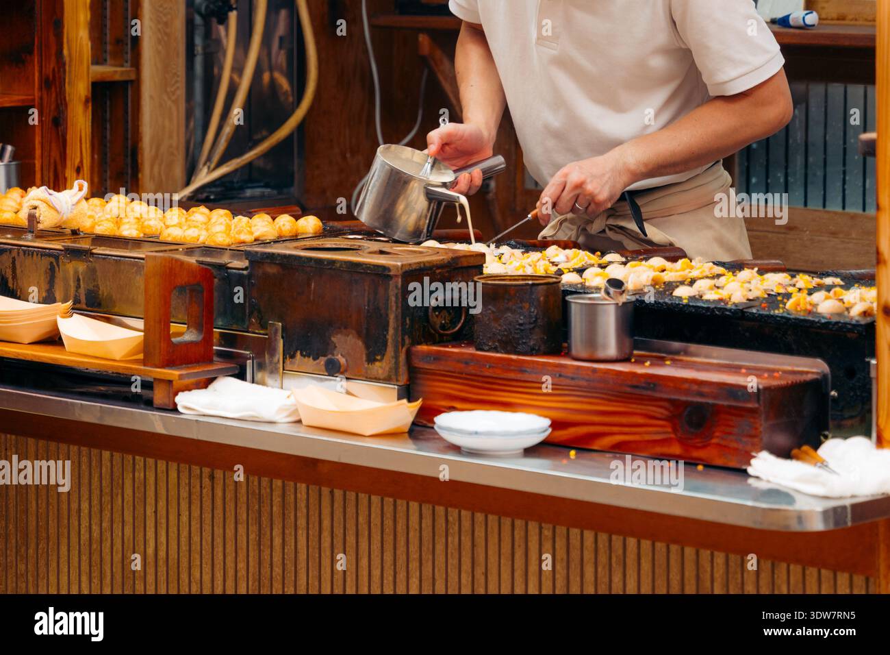 Lo chef di Osaka prepara il takoyaki, un popolare spuntino di Street food giapponese Foto Stock
