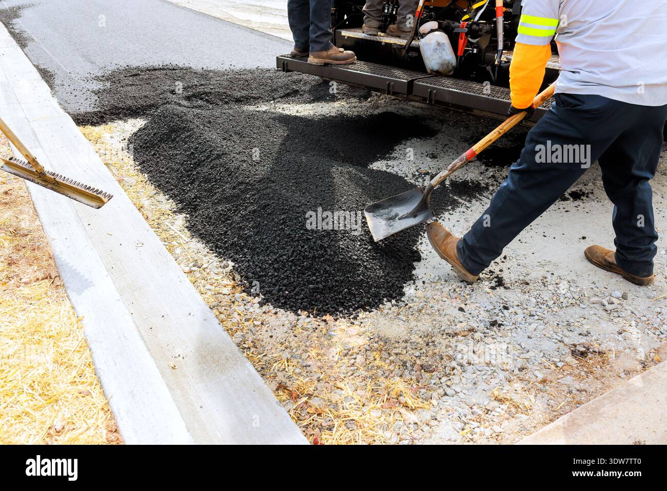 I lavoratori stanno posando asfalto per riparare la strada, utilizzando attrezzi e attrezzature Foto Stock
