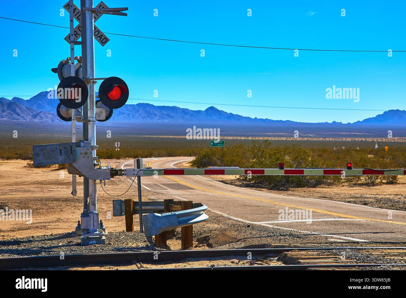 Railroad Crossing Barrier e Desert Road nel Mojave Landscape California Foto Stock