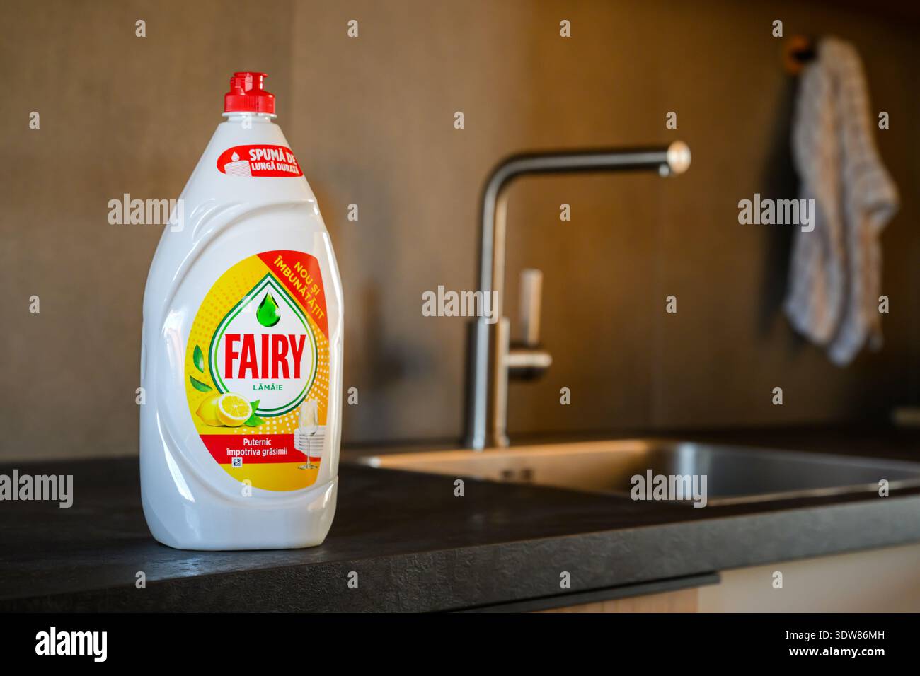 Novi Sad, Serbia - 25 febbraio 2026: Fotografia del prodotto di una bottiglia di liquido lavastoviglie bianca con tappo rosso, posizionata su un conto da cucina opaco scuro Foto Stock