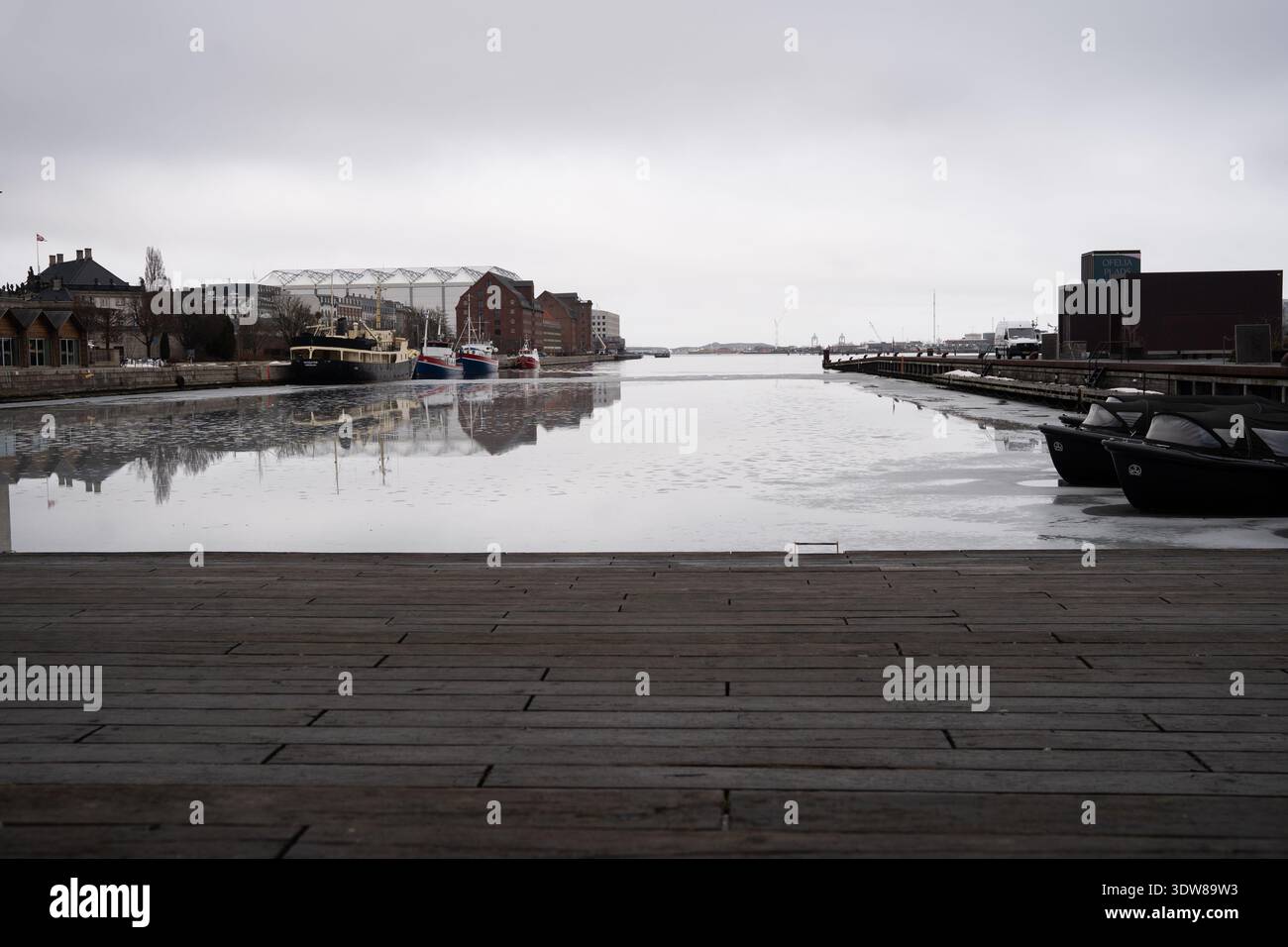 Tranquillo porto di Copenaghen con barche e riflessi in un giorno d'inverno coperto Foto Stock