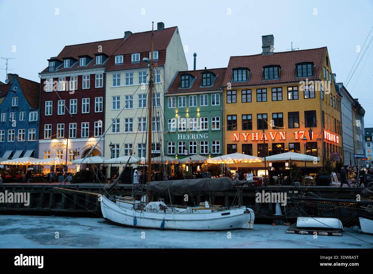 Colorati edifici storici e barche al porto di Nyhavn durante la sera d'inverno a Copenhagen Foto Stock