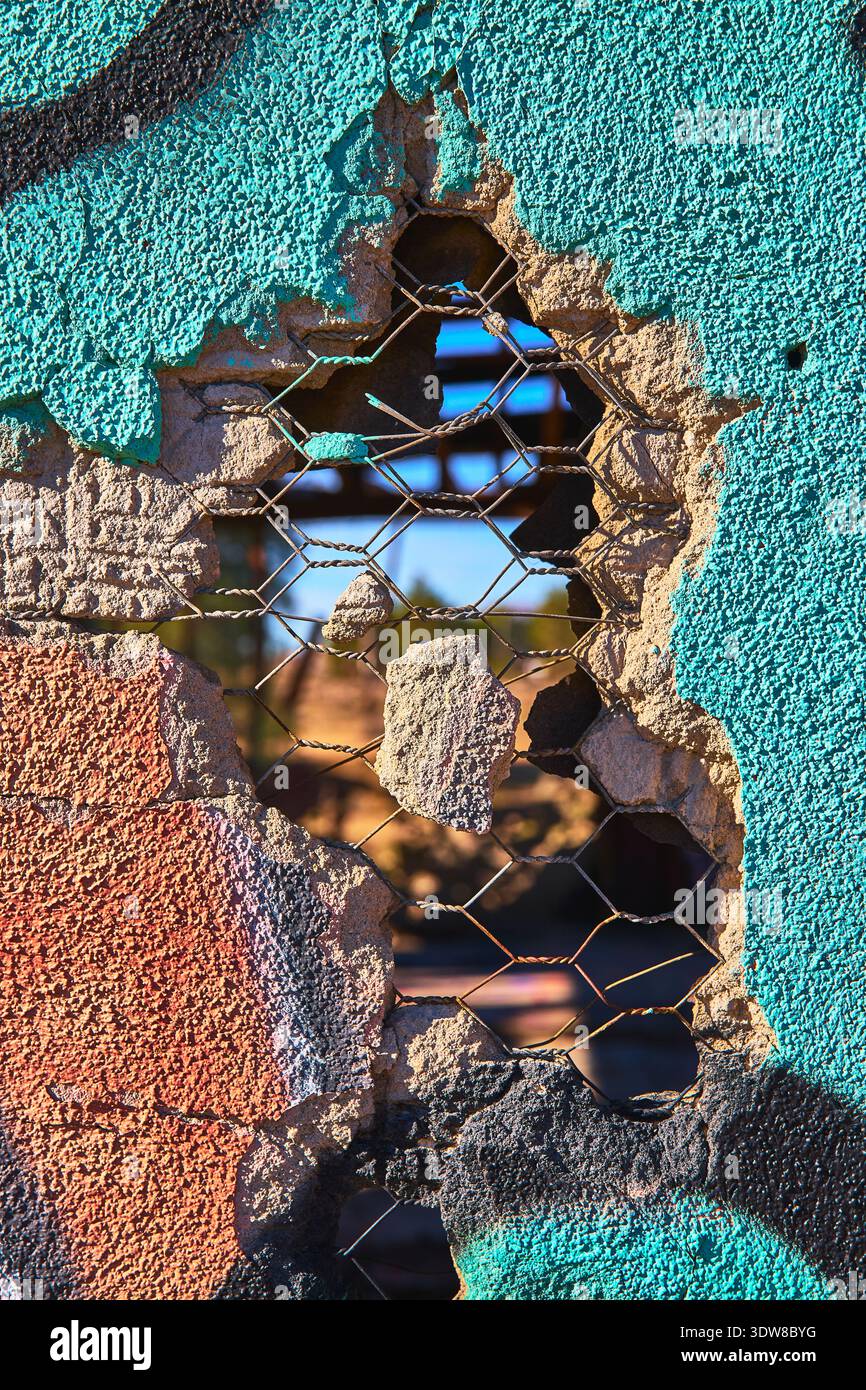 Texture murale abbandonata con buchi e rete metallica nella luce del sole dettaglio di decadimento urbano Foto Stock