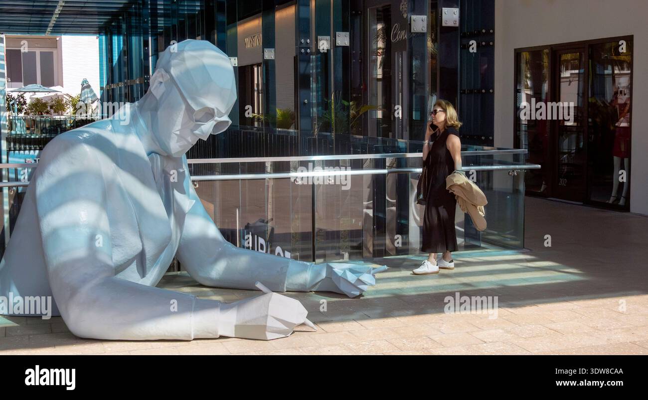 Una donna parla con uno smartphone in un centro commerciale nel Design District, Miami, Florida, Stati Uniti Foto Stock