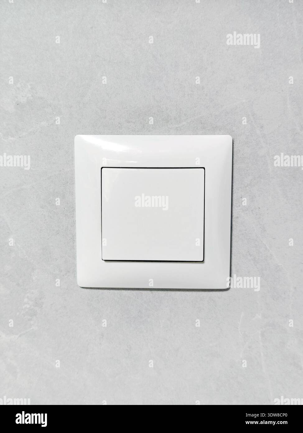 Su una parete grigio chiaro, c'è un interruttore bianco quadrato per la luce elettrica. Dotazioni interne: Premere il pulsante di accensione. Foto Stock