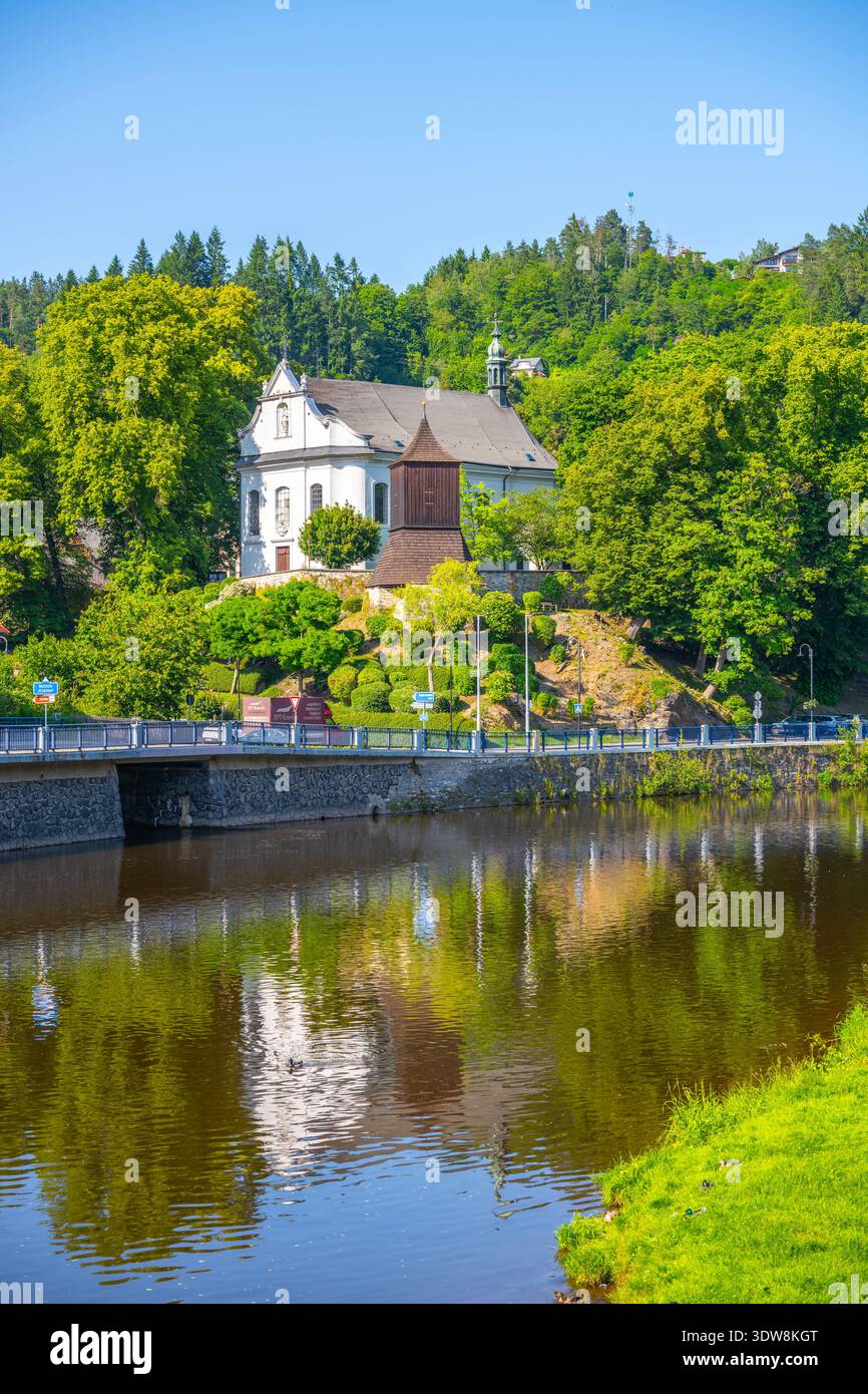 La chiesa di San Giacomo maggiore si trova a Zelezny Brod. Si vede su una collina circondata da alberi e che si riflette nel fiume vicino. La scena mostra il cielo blu e la natura verde. Foto Stock
