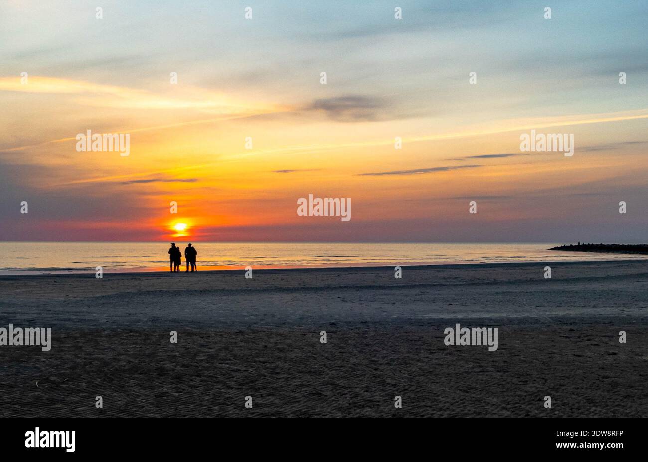 Due coppie sagomate al tramonto sul mare in Lettonia Foto Stock