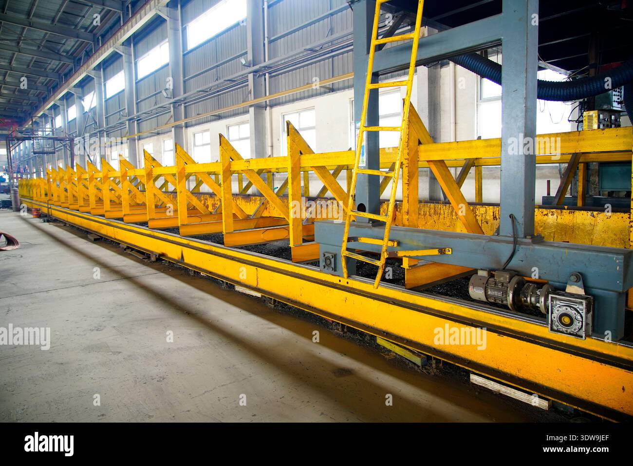La piattaforma di saldatura automatica della trave H in officina di strutture in acciaio pesante, con telaio di supporto giallo e testa di saldatura precisa, è il cuore Foto Stock