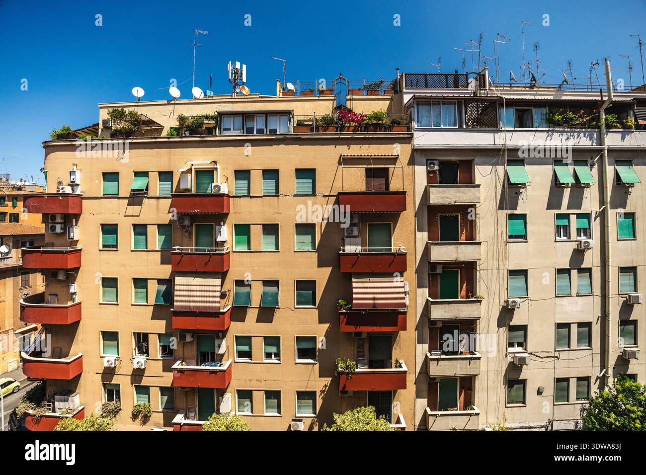 Edifici residenziali con balconi, persiane e antenne sul tetto in una giornata di sole a Roma, Italia Foto Stock