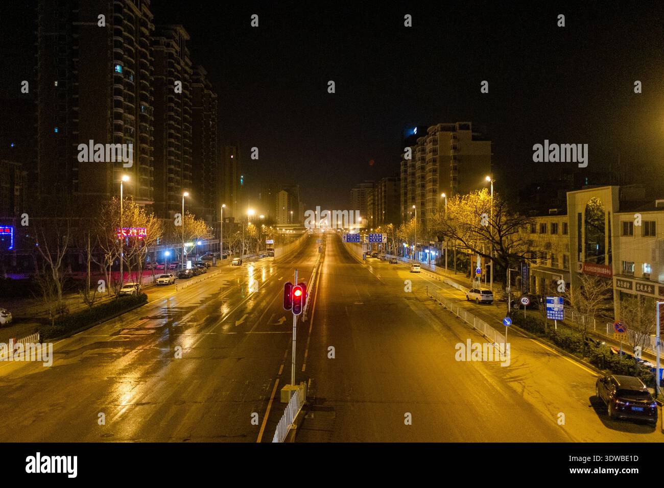 Wuhan, provincia di Hubei, Cina - 16 marzo 2018: Lunghe piste di esposizione dei fari dei veicoli su un'ampia strada urbana fiancheggiata da edifici residenziali a nig Foto Stock