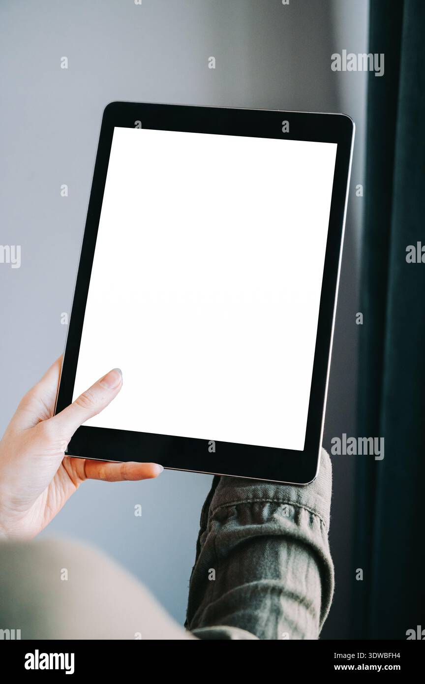 Primo piano di una persona che tiene un tablet con schermo bianco vuoto all'interno. Composizione minimale e moderna, ideale per presentazioni di app, mockup di siti Web, digitale Foto Stock