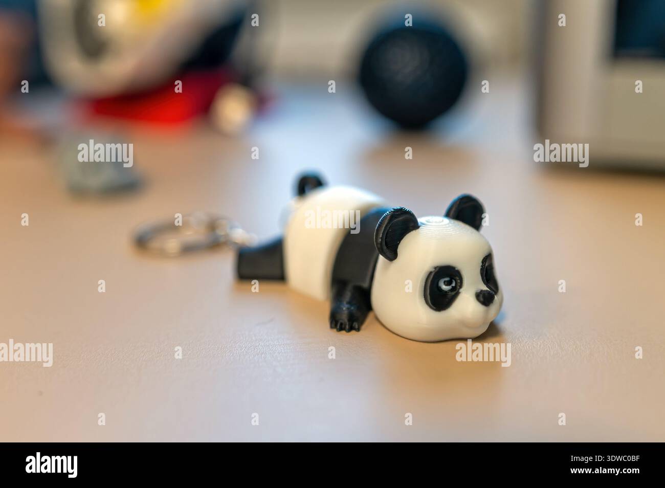 Un carino portachiavi di panda si trova su un tavolo vicino ad altri piccoli oggetti in un ambiente luminoso. Foto Stock