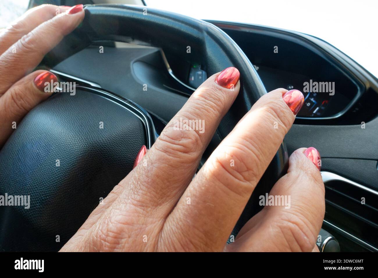 le mani di un vecchio con rughe dell'età e una manicure femminile rossa. Unghie allungate sulle mani degli uomini. Le mani degli uomini con le unghie rosse giacciono sul volante di un Foto Stock