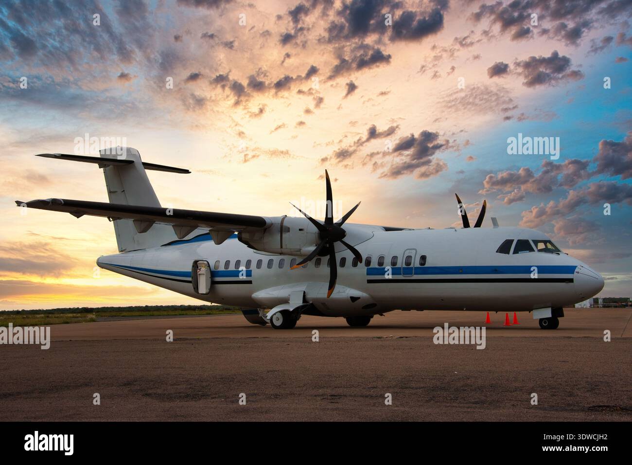 l'aereo commerciale bimotore è parcheggiato sull'asfalto in un campo d'aviazione durante il bellissimo tramonto o l'alba con le nuvole Foto Stock
