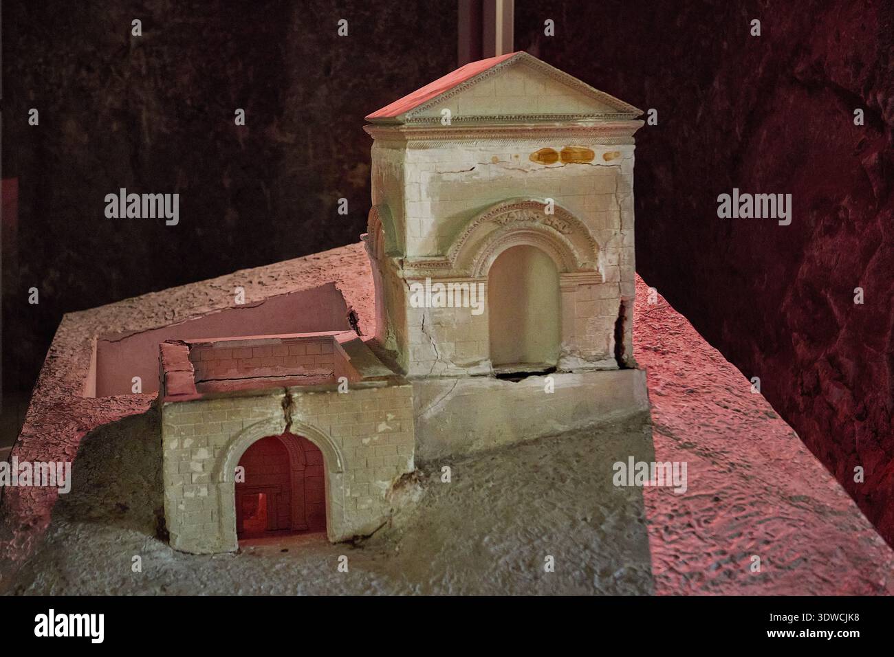 Modello architettonico di edificio antico esposto nel museo, caratterizzato da dettagliate opere in pietra e ingresso ad arco, illuminato con luce soffusa Foto Stock