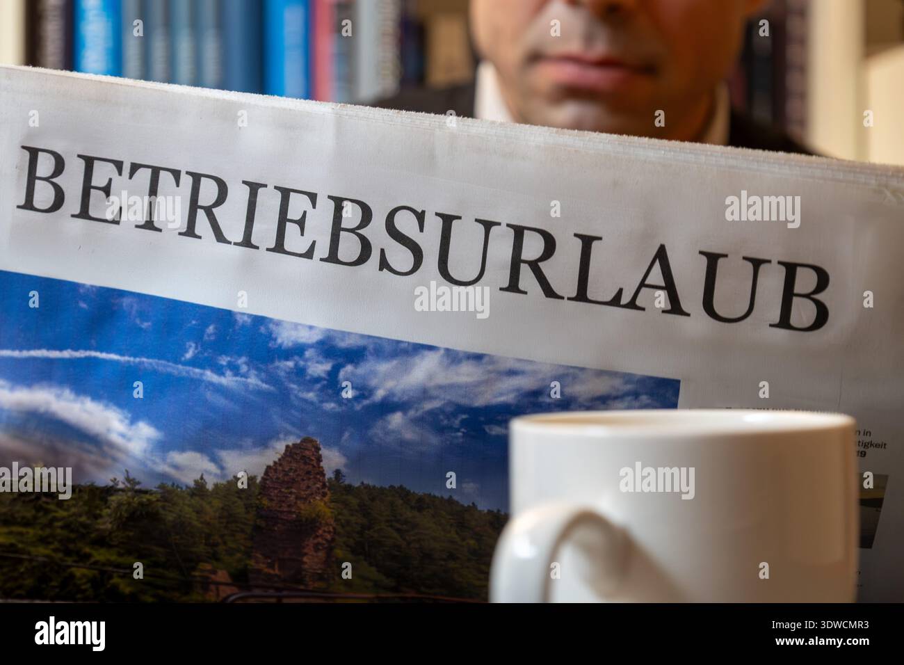 Uomo che legge un giornale (simbolico) con il titolo BETRIEBSURLAUB (festività aziendali) Foto Stock