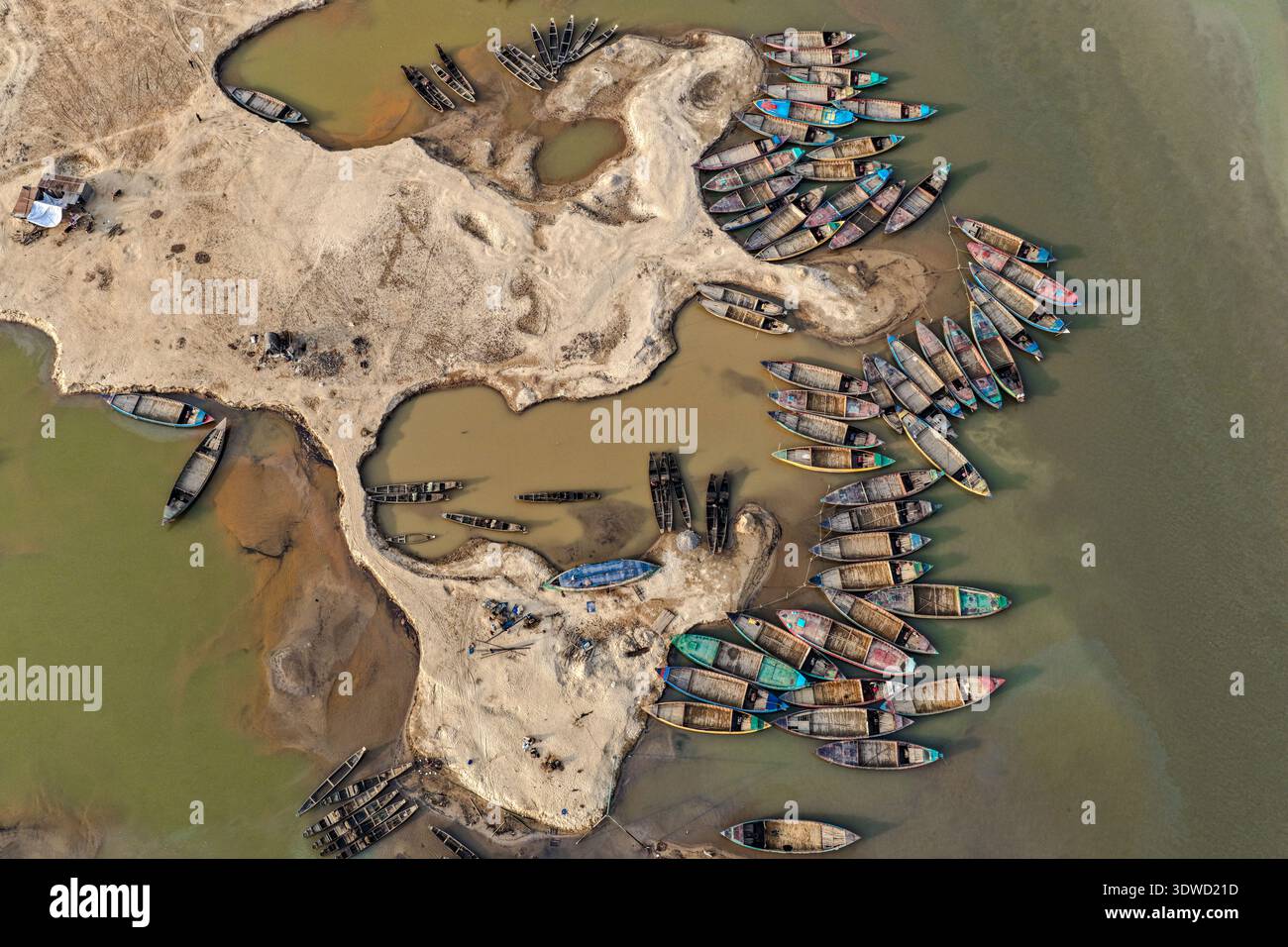 Vista aerea di numerose barche colorate raggruppate intorno alle rive sabbiose, che creano un vivace mosaico contro i toni terrosi dell'acqua, Sylhet, Sylh Foto Stock