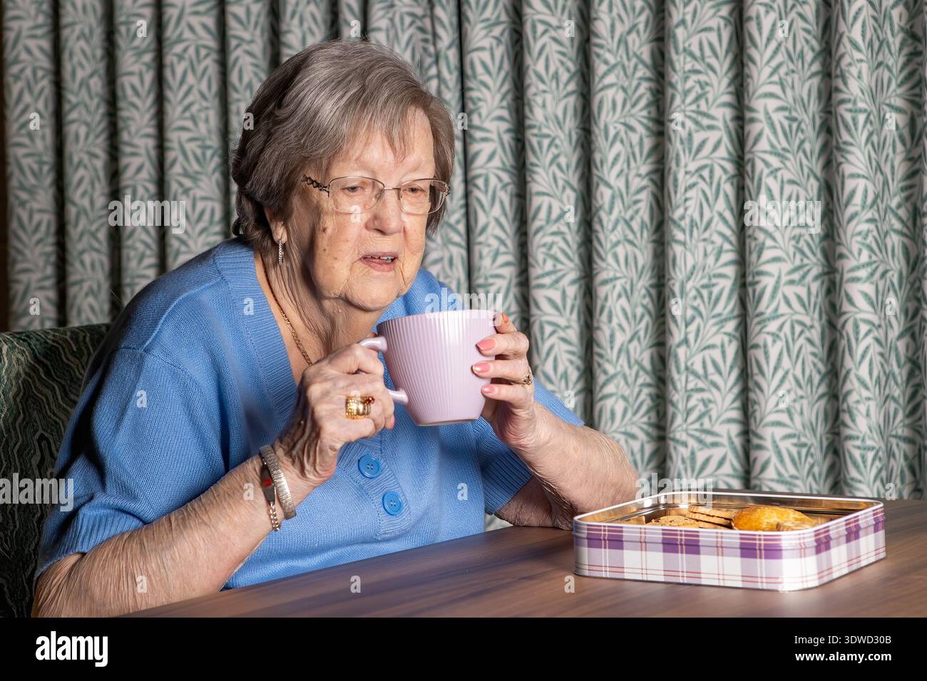 nonna di 86 anni con tè e biscotti Foto Stock