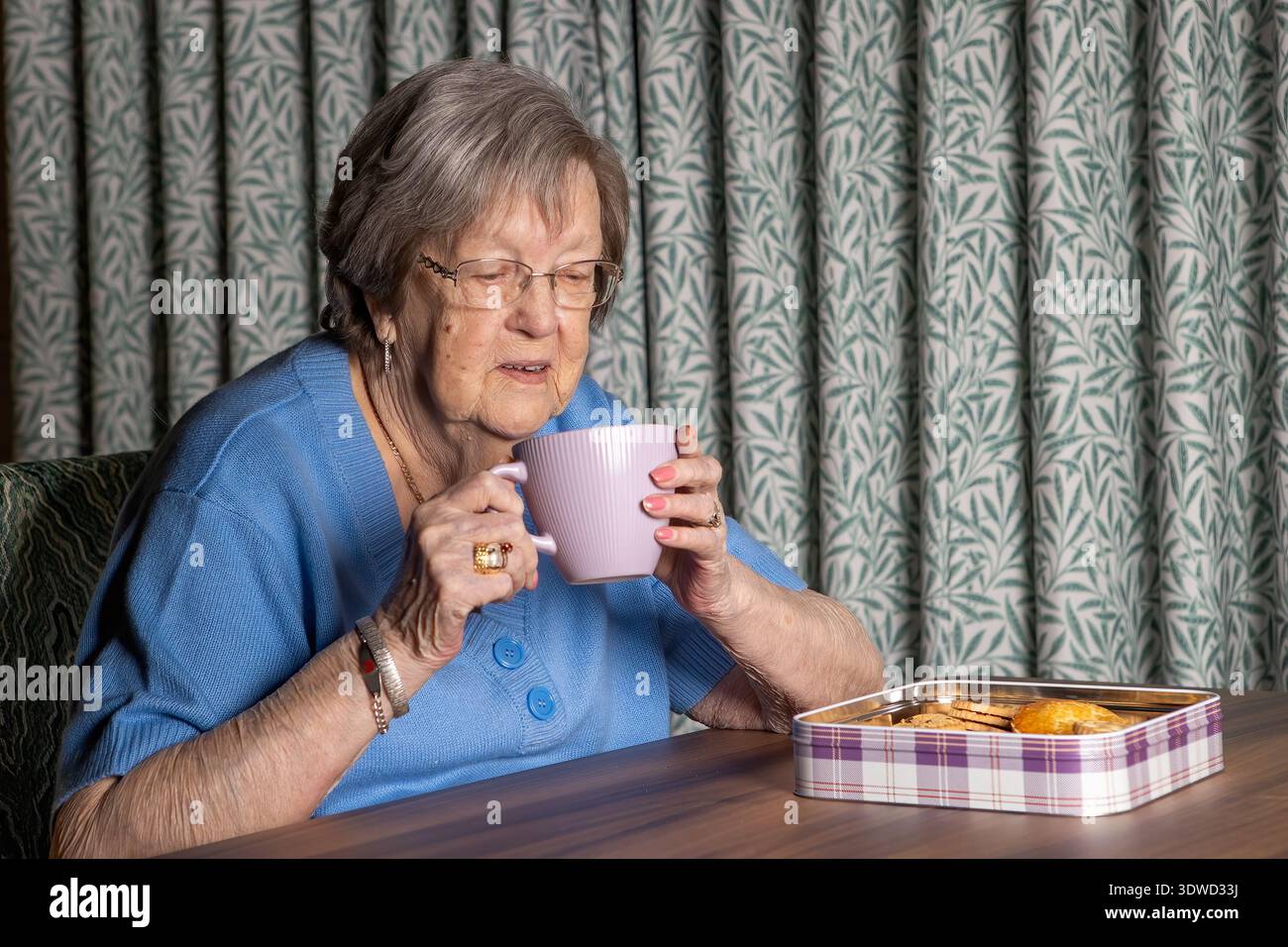 nonna di 86 anni con tè e biscotti Foto Stock