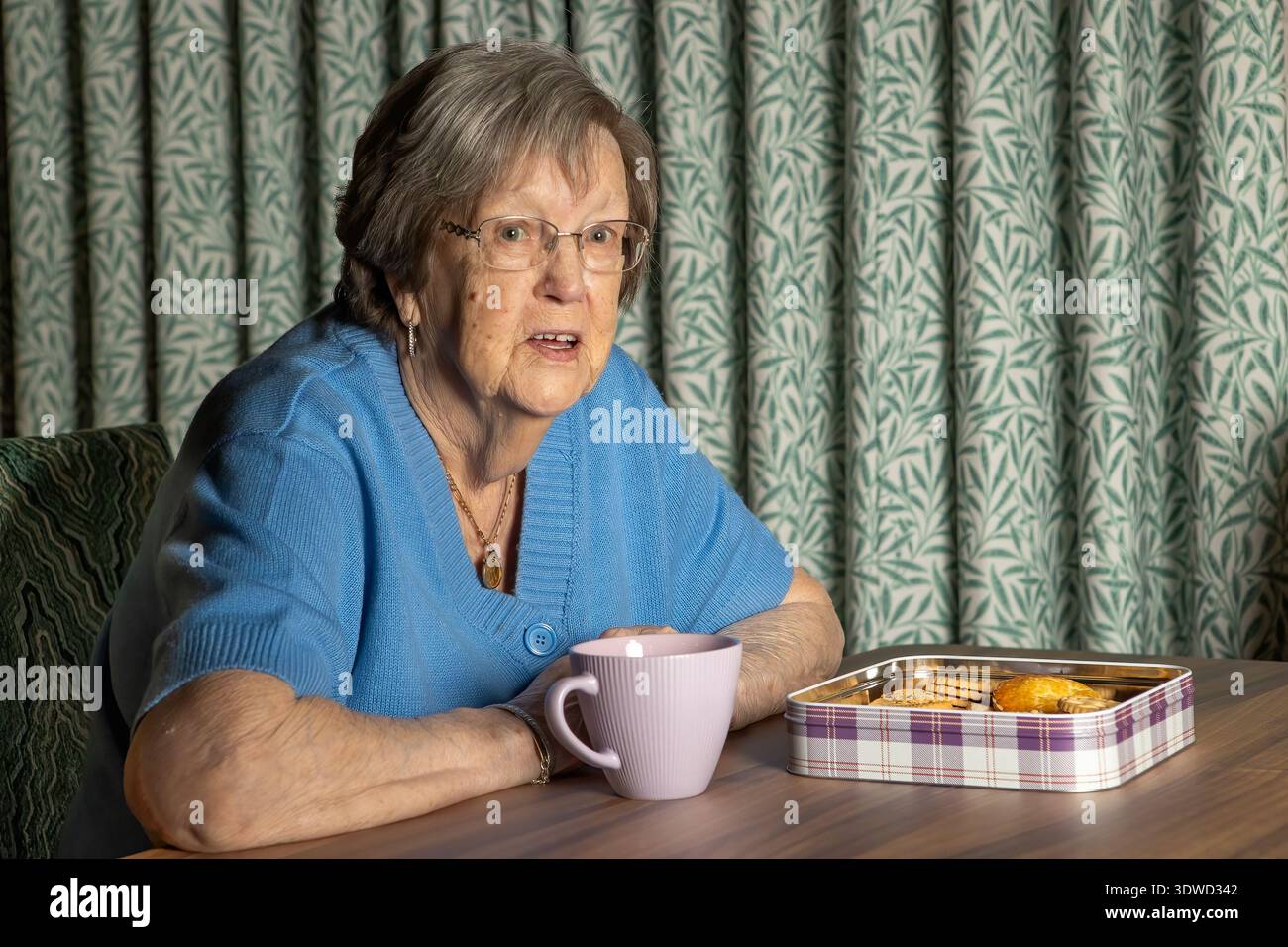 nonna di 86 anni con tè e biscotti Foto Stock