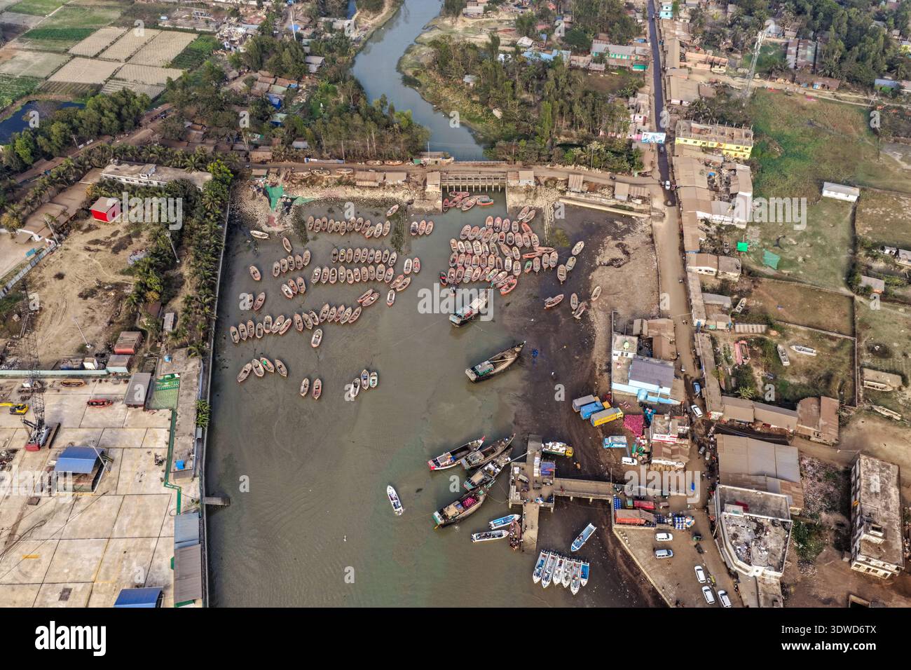Sitakund, Bangladesh - 19 febbraio 2026: Vista aerea di un vivace porto dove i pescherecci affollano le acque torbide vicino ai moli di cemento, riflessi Foto Stock