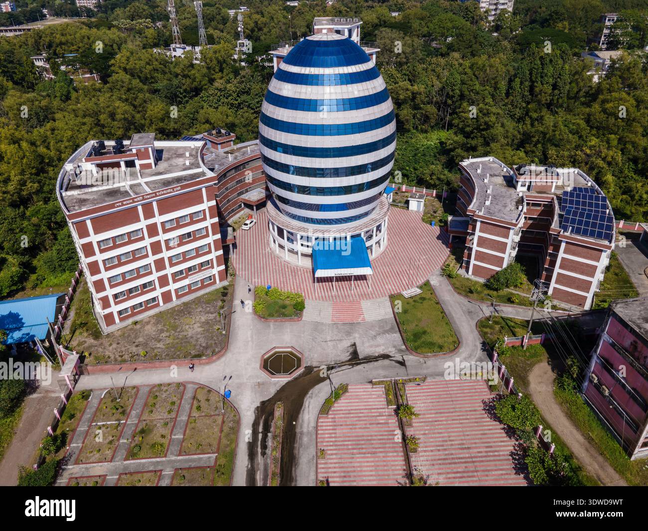 Chattogram, Bangladesh - 1 dicembre 2023: Veduta aerea del caratteristico edificio a forma di uovo, le sue strisce blu e bianche contrastano con il rosso-bri Foto Stock