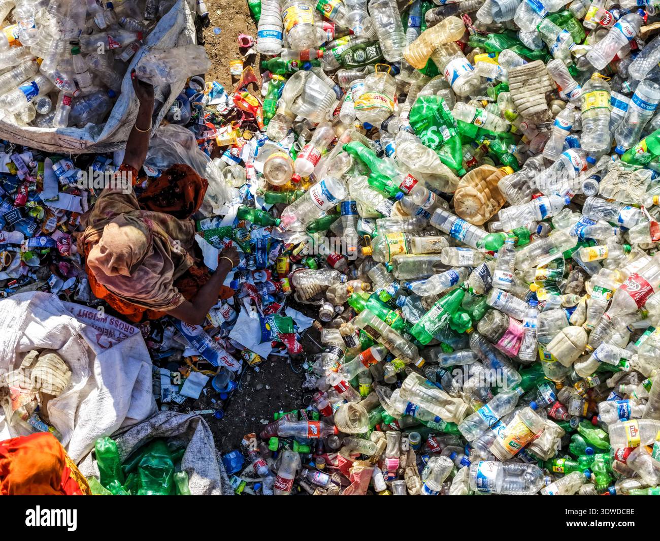 Vista aerea di un lavoratore in mezzo a un mare di bottiglie di plastica scartate, un netto contrasto tra lo sforzo umano e i rifiuti schiaccianti, Chattogram, Chittagong Foto Stock
